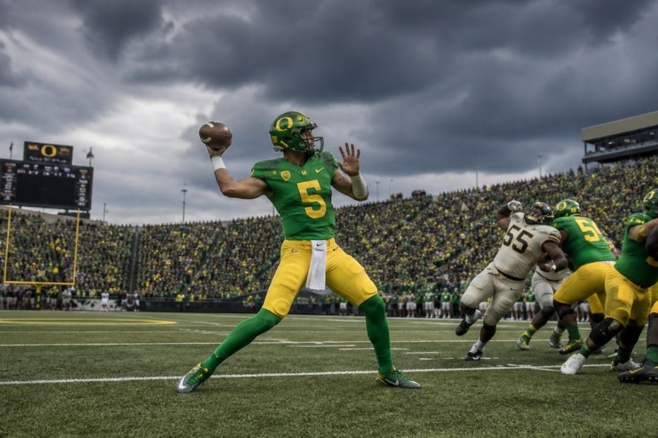 Oregon Ducks quarterback throwing a pass during a storm-delayed game against Oklahoma State