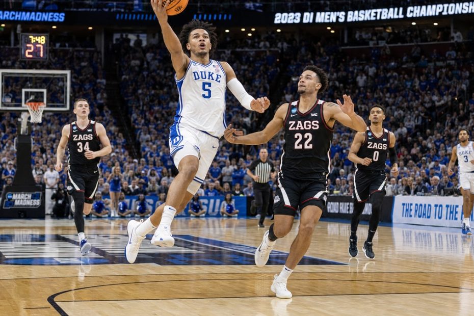 College basketball player driving to the basket during a March Madness NCAA tournament game in a packed arena